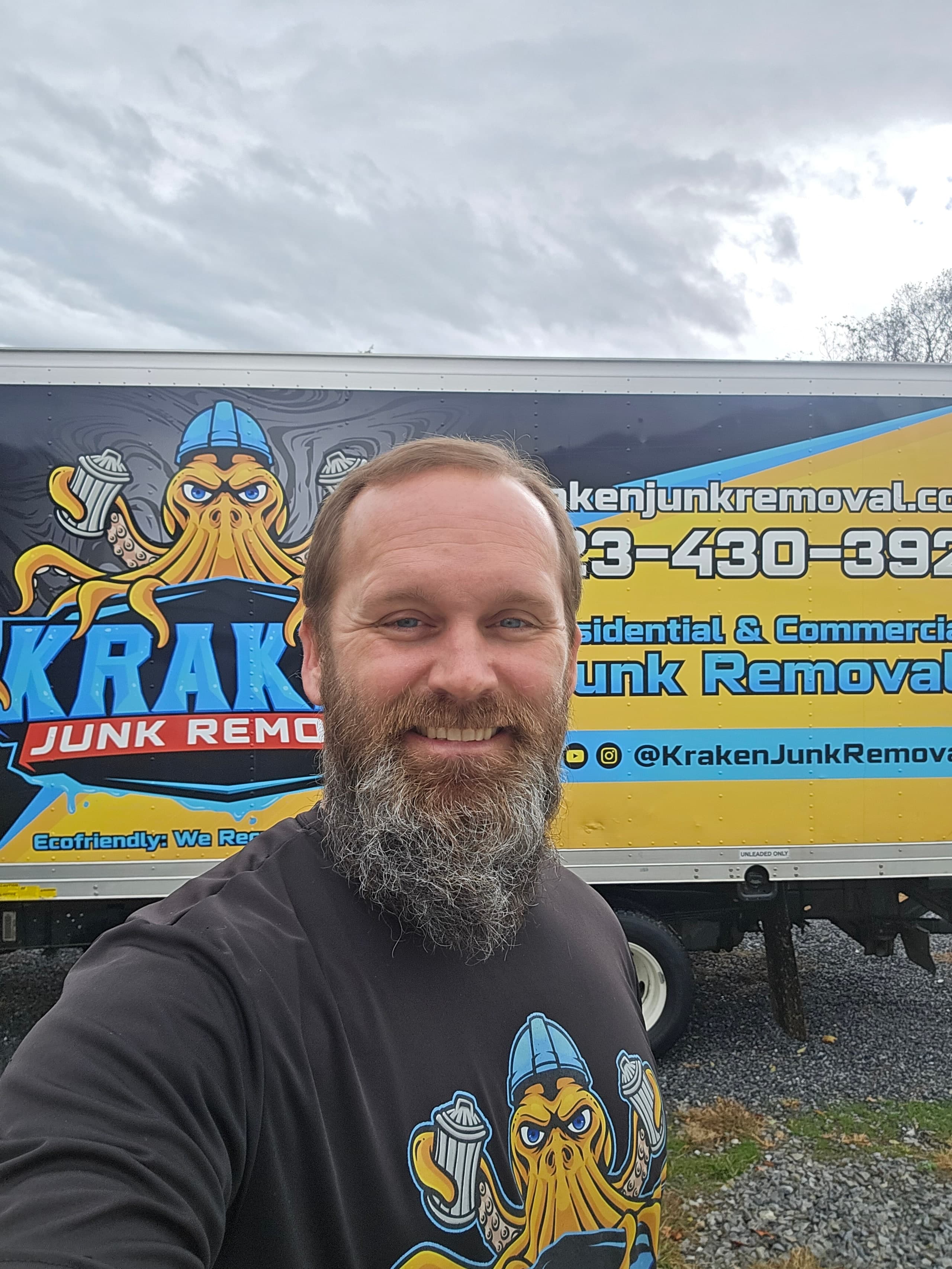 Austin, owner of Kraken Junk Removal, beside the company truck
